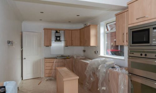 Scene inside a house undergoing a kitchen refurbishment after the cabinets are partially fitted and the appliances installed.