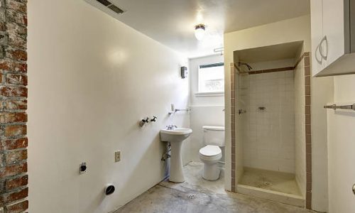 Empty white bathroom under construction. View of  concrete floor and open shower